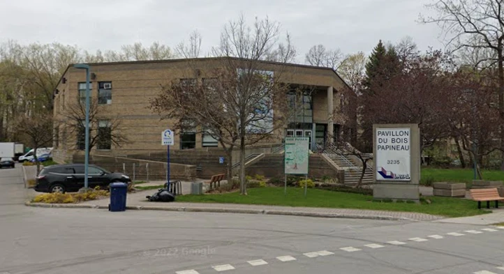 Low brick community building with front stairs, surrounded by trees and parking area.